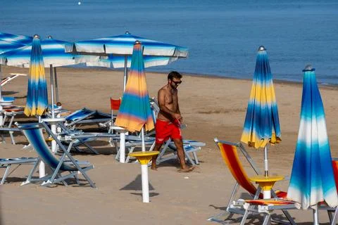 Man Walking Between Beach Umbrellas and Sun Loungers Stock Photos