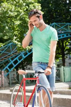 Man walking with a bicycle and talking on a mobile phone, Paris, Ile-de-France, Stock Photos