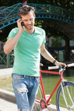 Man walking with a bicycle and talking on a mobile phone, Paris, Ile-de-France, Stock Photos