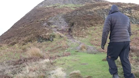 Man walking a big hill Stockbeeldmateriaal 229984899