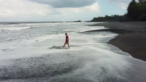 Man walking on black sand beach before storm Stock Footage 157908312