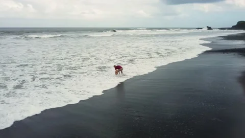 Man walking on black sand beach before storm Stock Footage 158097802