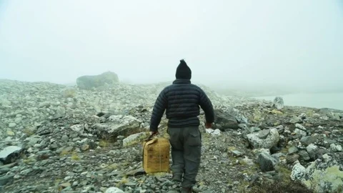 Man walking with a box on the hill of rubble Stock Footage 77450843