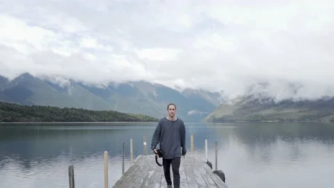 Man walking with a camera on the wooden bridge at rotoiti lake, new zealand Stock-Footage 220777891