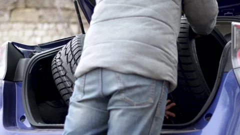 Man walking carrying and putting some winter tires in car trunk Stock-Footage 224660341