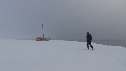 Man walking to a catamaran in the ice floe, Arctic Ocean Video stock 104871003