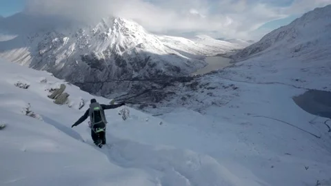 A man walking cautiously and dangerously down a snow covered mountain trail Video stock 146649763