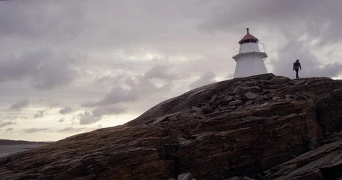 Man walking up a cliff to a lighthouse. Stock Footage 106121244