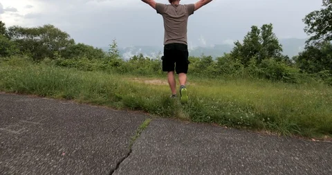 Man is walking close to the mountain edge and raising his hands to the sky. Stock-Footage 91755473