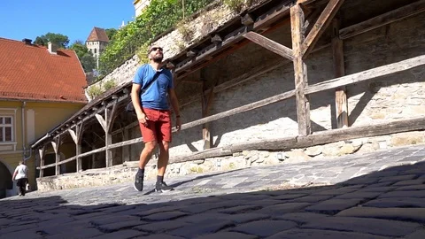 Man walking on cobblestone which lead him to the castle, slow motion shot at 240 Stock Footage 103500545