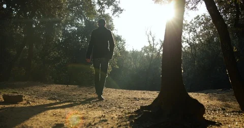 Man walking in cold forest during sunrise, shot from behind WS 스톡 동영상 122763961