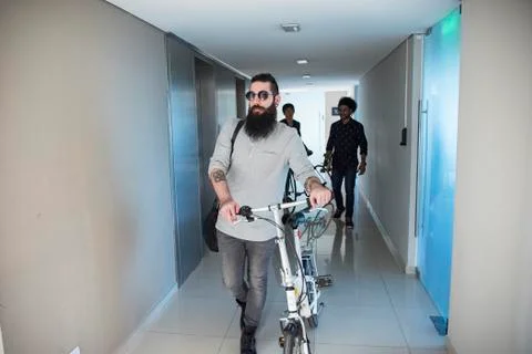 Man walking in corridor with bicycle Stock Photos