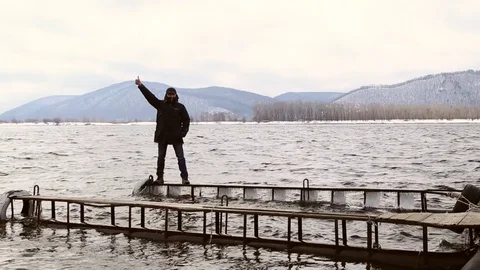 Man walking dangerously on a narrow icy pier Stock Footage 74160254