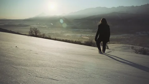Man Walking in Deep Snow against the Sunrise with Mountains in the background Stock Footage 93155509