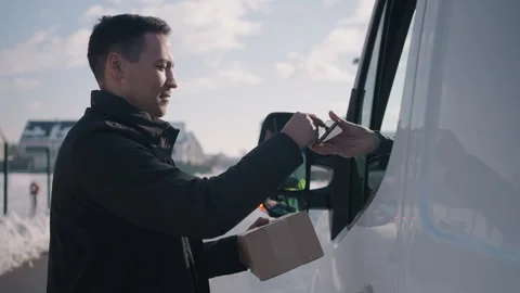 Man walking up to the delivery van, where the delivery man hands out a parcel 스톡 동영상 263894628