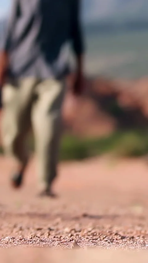 Man Walking on Desert Path Wearing Sandals, Low Angle Travel Shot - 4K Vertical Stock Footage 328130541