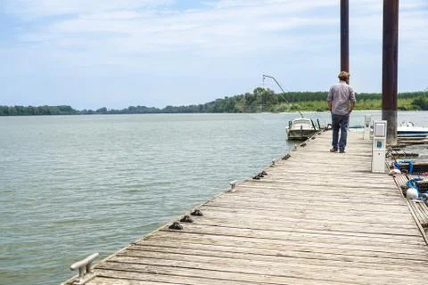 Man walking on dock away from the camera on the river pier Stock Photos