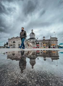 Man walking dog on rainy day in square with building in background. Fotos de archivo