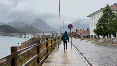 Man walking with dog through rainy mountain village in Spain 動画素材 339216634