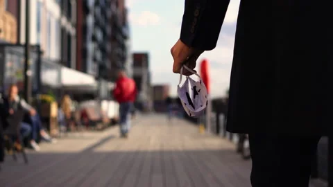 Man Walking Down a Boardwalk with Protective Face Mask in Hand Stock Footage 132502587