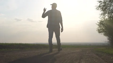 Man walking down dirt road. Silhouette of farmer walking in a field. Farmer Video stock 316467437