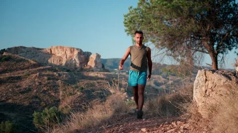 Man walking down a dry, rocky mountain path at golden hour, moving with ste.. Stock Footage 340995642