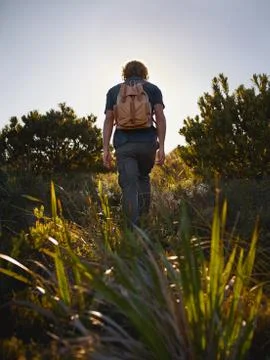 Man walking down the hill with backpack Stock Photos