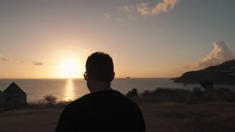 A man is walking down the hill with the ruins of an abandoned house Stock Footage 194156580