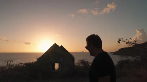 A man is walking down the hill with the ruins of an abandoned house Stock Footage 194158670