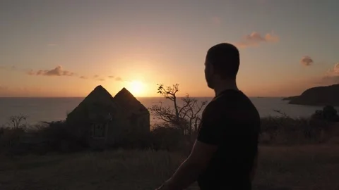 A man is walking down the hill with the ruins of an abandoned house Stock Footage 194158847