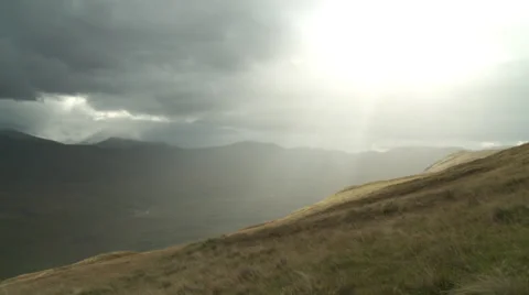 Man walking down the hill as sky breaks through clouds Stock Footage 33387496