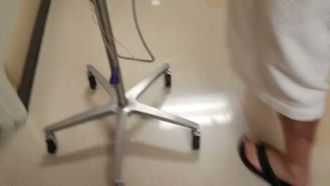 A man walking down a hospital hall with an IV stand Stock Footage 100862227