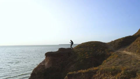 The man walking down the mountain on the seascape background Stock Footage 143568662