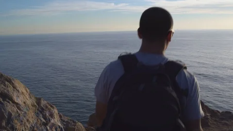 Man walking down a path, overlooking ocean from a cliff, 4k Stock Footage 103438116