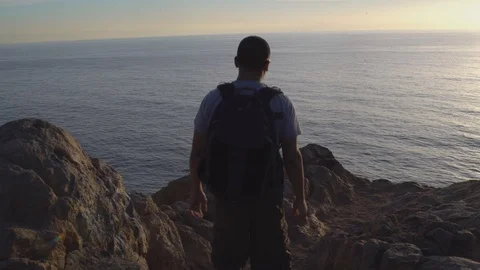 Man walking down a path, overlooking ocean from a cliff, 4k Stock Footage 103438166