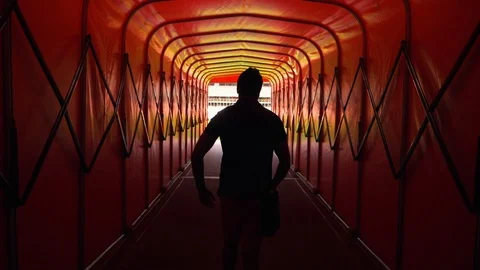 A man walking down a red tunnel to a football, soccer stadium. Stock Footage 114993786