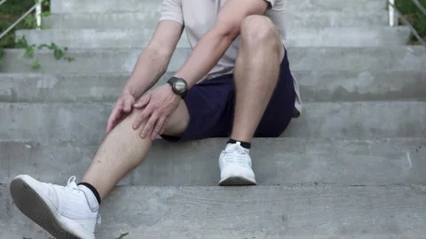 A man walking down the stairs feels a sharp pain in his calf muscle. Stock Footage 253864509