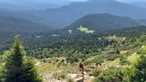 A man is walking down a steep mountain with trekking poles Stock Footage 250363400