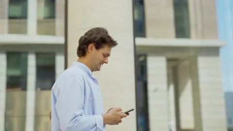 Man walking down street and texting on phone Stock Footage 134574823