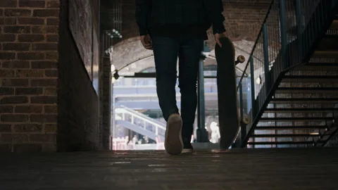Man walking down the street holding a skateboard Stock Footage 133635120