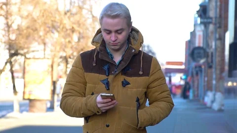 The man is walking down the street with a smartphone in his hands Stock Footage 86048037