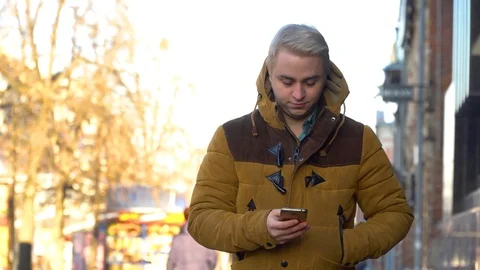 The man is walking down the street with a smartphone in his hands Stock Footage 86048110