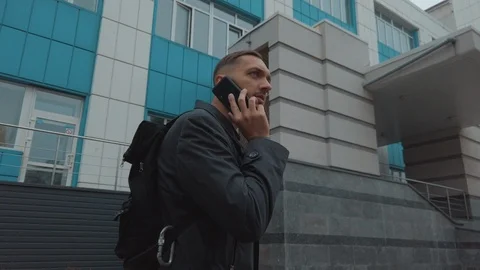 A man walking down the street talking on the phone Видео 119150705