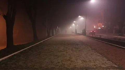 A man walking down the street through the fog. Cars in fog. Street lights. Stock Footage 45085579