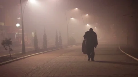 A man walking down the street through the fog. Cars in fog. Street lights. Stock Footage 45090731
