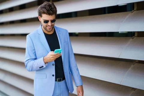 Man walking down the street using his smartphone with a happy expression Stock Photos