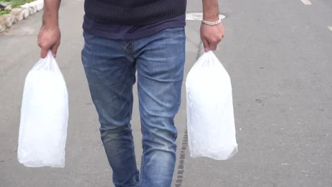 A man walking down the track carrying two ice bags on a friends trip to the Stock-Footage 155784137