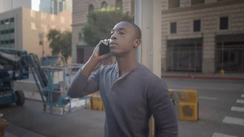 Man walking in downtown while on his phone 스톡 동영상 98912621