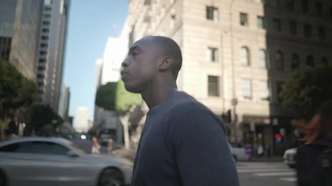 Man walking in downtown while on his phone 스톡 동영상 98912728