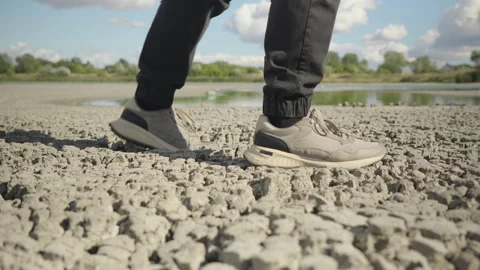 Man Walking on the Dried Bed of a Lake After Extreme Heat Stock Footage 344890595